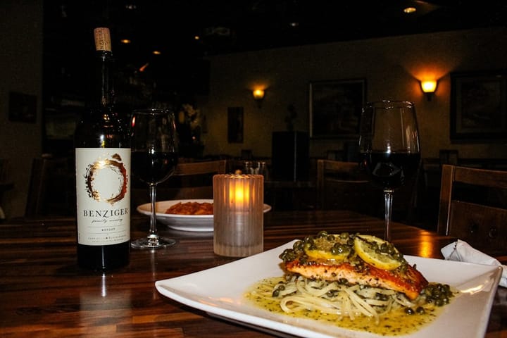 A beautifully arranged table featuring pasta dishes paired with elegant wine glasses, showcasing a culinary fusion.