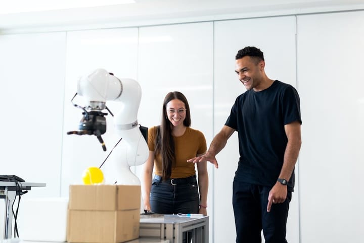 A futuristic AI agent analyzing blueprints, with an engineer reviewing the design, highlighting collaboration in tech.